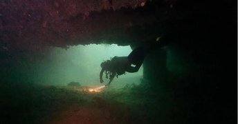 dive-sites_a-diver-with-a-torch-exploring-inside-a-wreck
